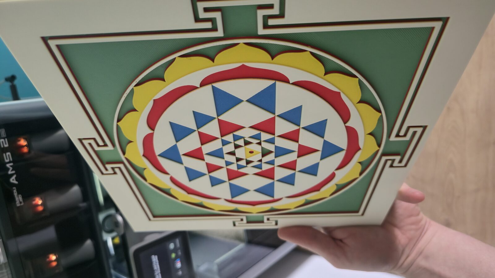 Hand holding the Sri Yantra panel, showing its slim 3.5mm profile